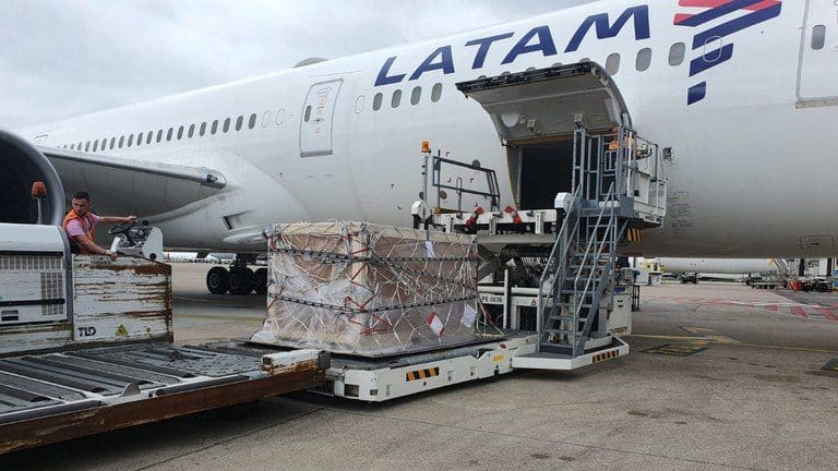 Palete de caixas cintadas sobre o elevador de carga, junto ao porão de um avião de passageiros no pátio do aeroporto