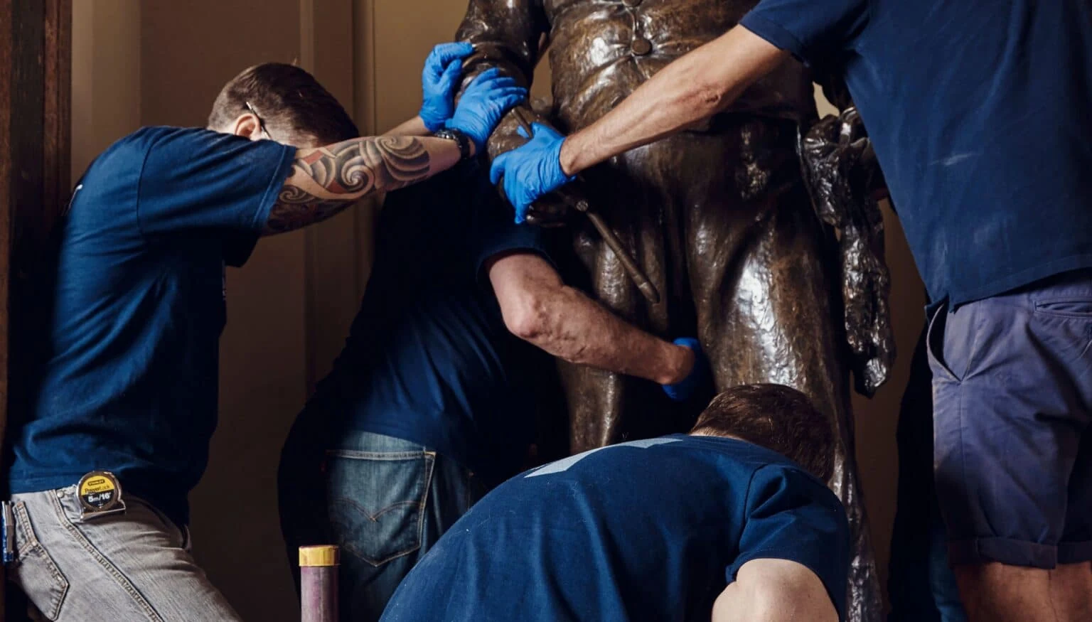 Four specialized Momart employees handling a sculpture.
