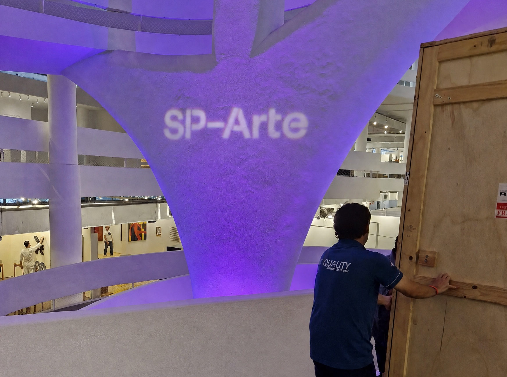 Equipe abre uma caixa de transporte na sala de exposição, diante do público